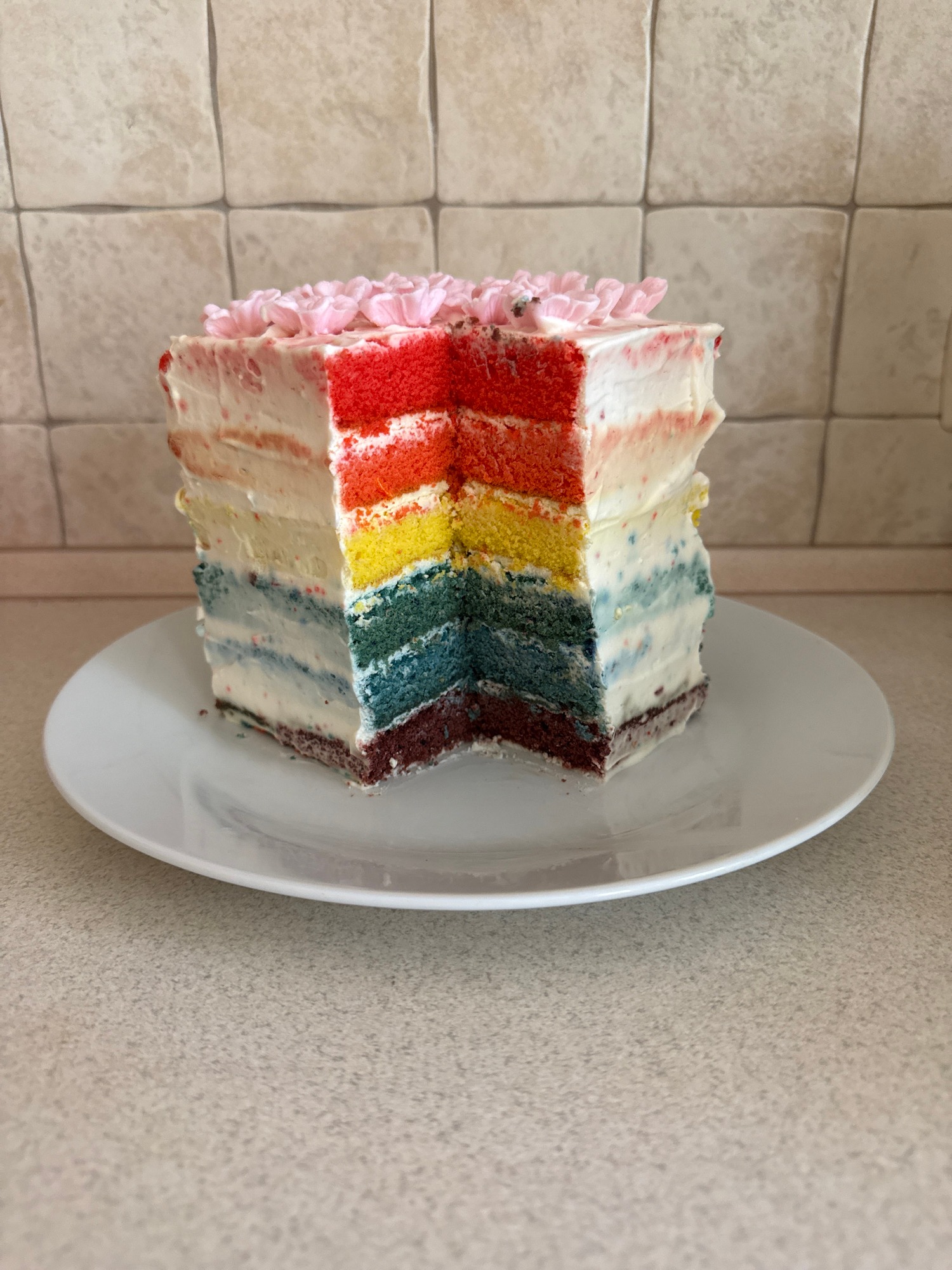 Rainbow layer cake with pink flowers, sliced and plated