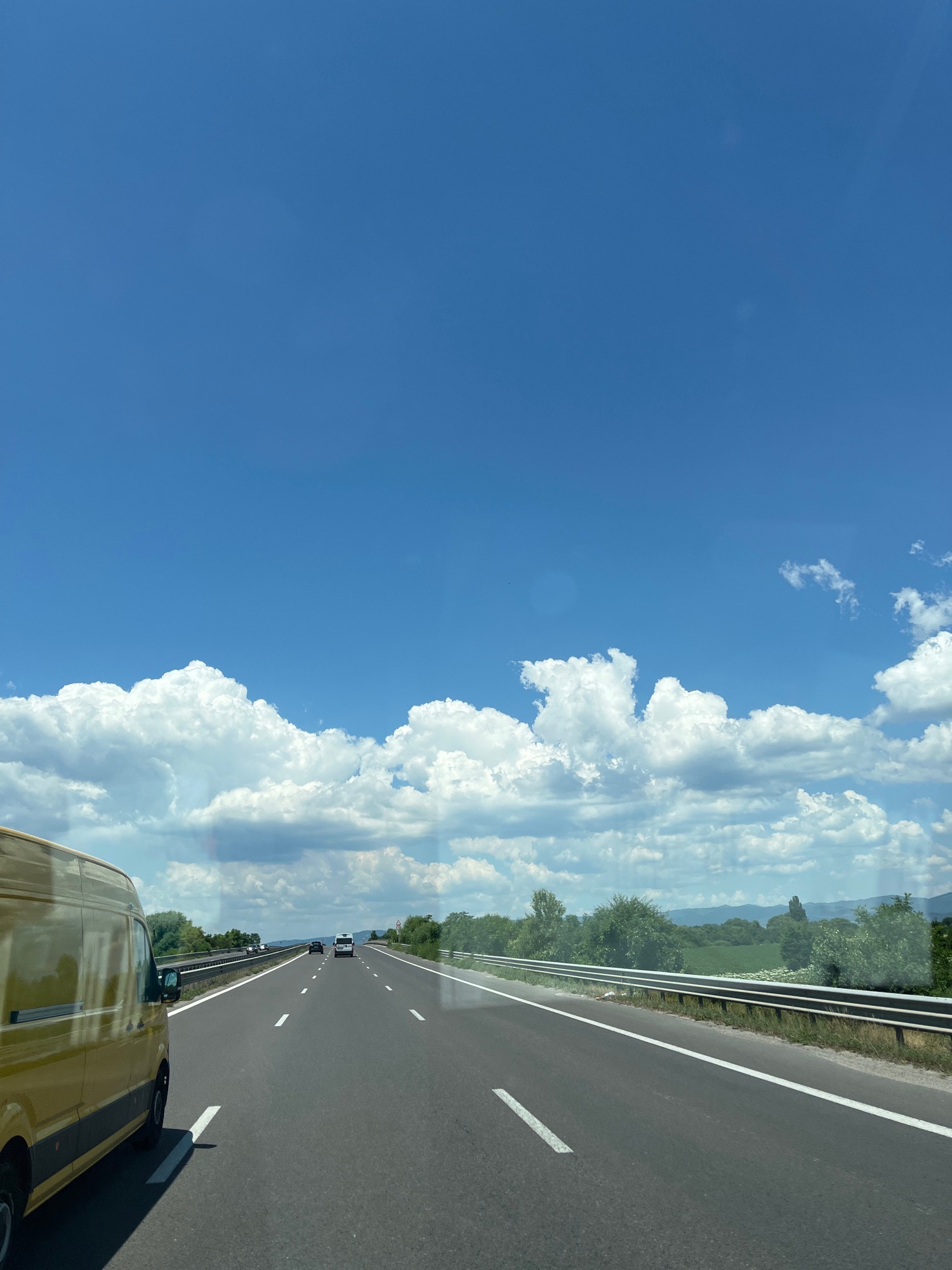 Highway drive through open countryside under a dramatic summer sky
