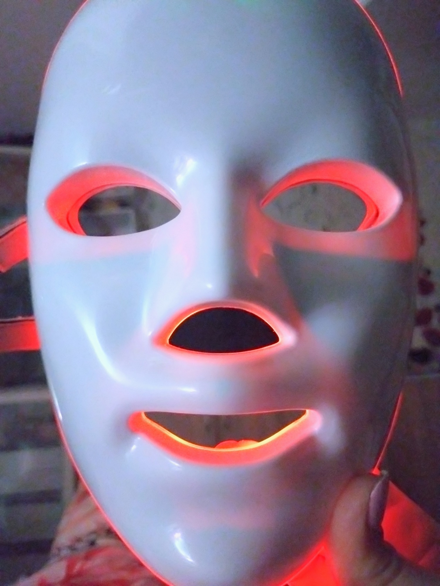 LED face mask examined against a city sunset backdrop