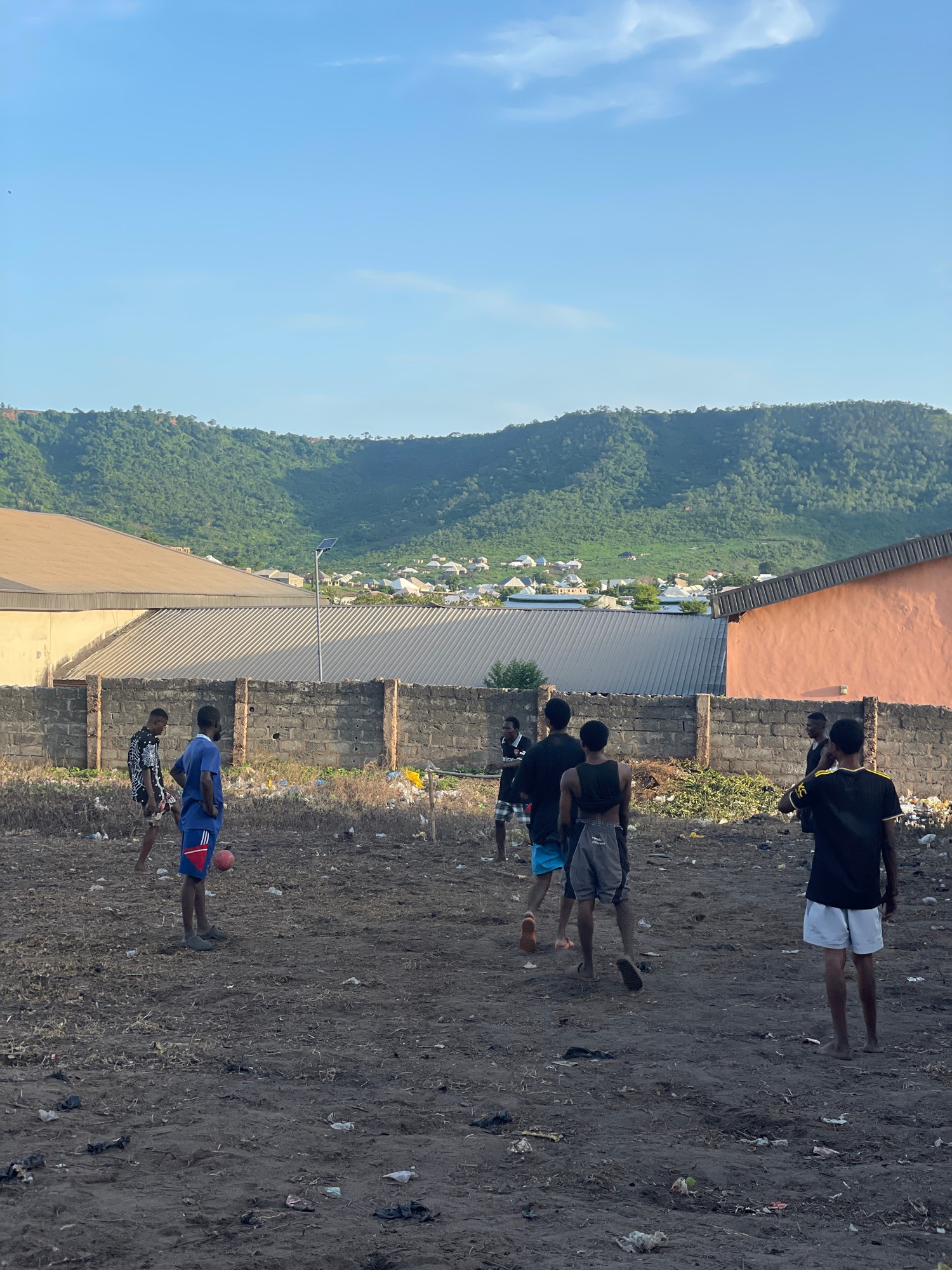 Pickup soccer on a rough dirt lot in a semi-urban neighborhood