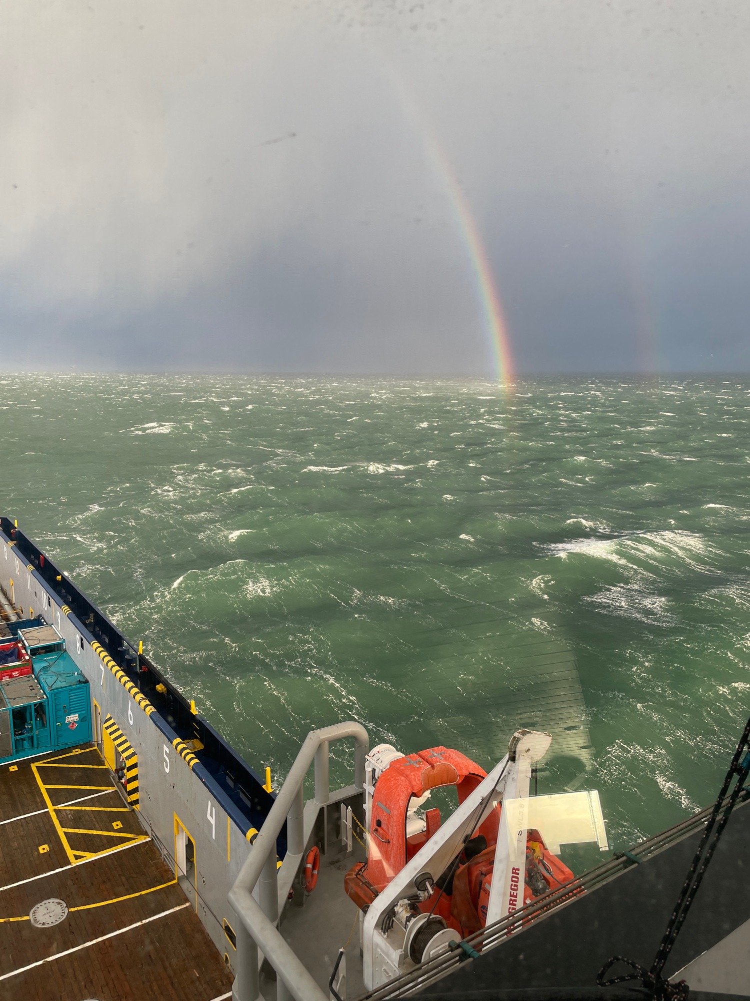 Voyage at Sea: Rainbow Arches Over Turbulent Waters