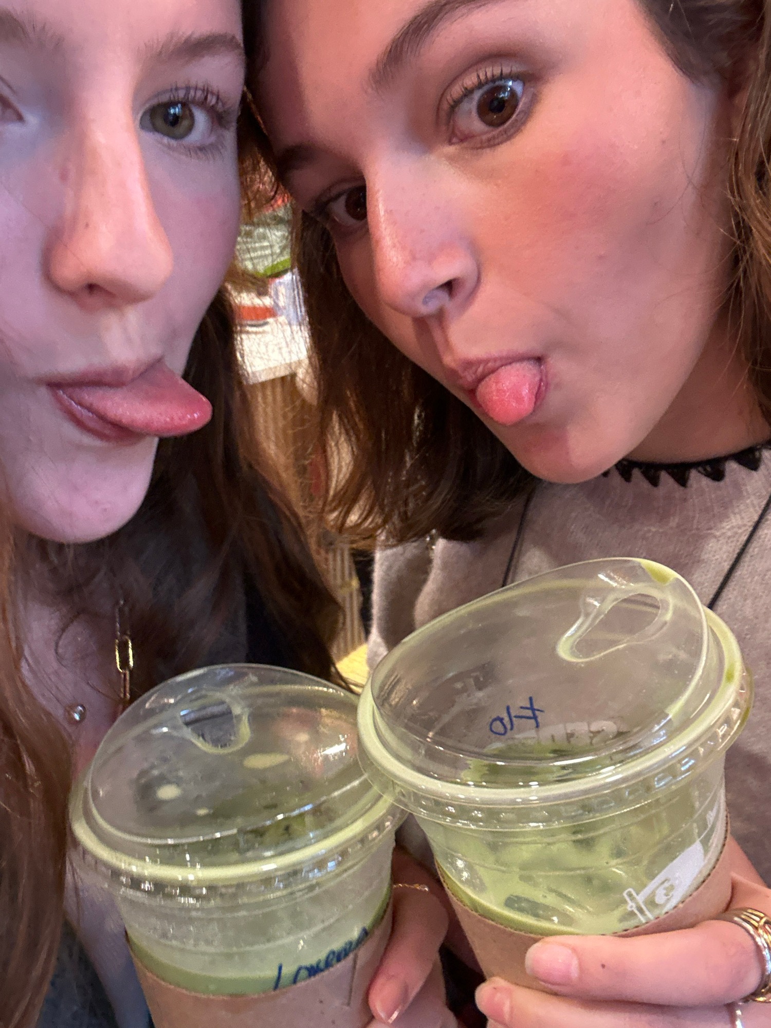 Young women socializing with drinks and taking selfies indoors