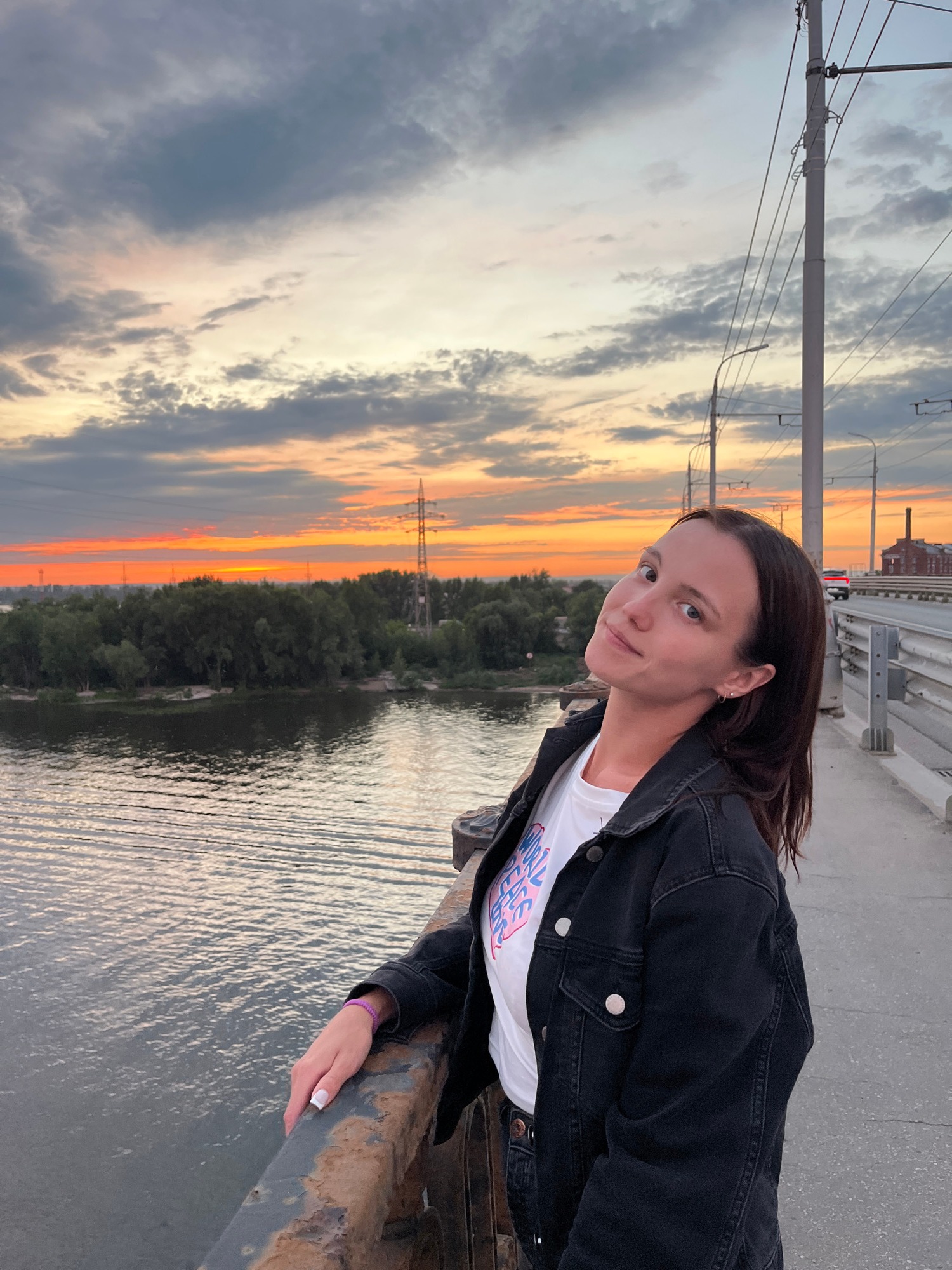 Leaning on a rust-colored bridge railing at sunset