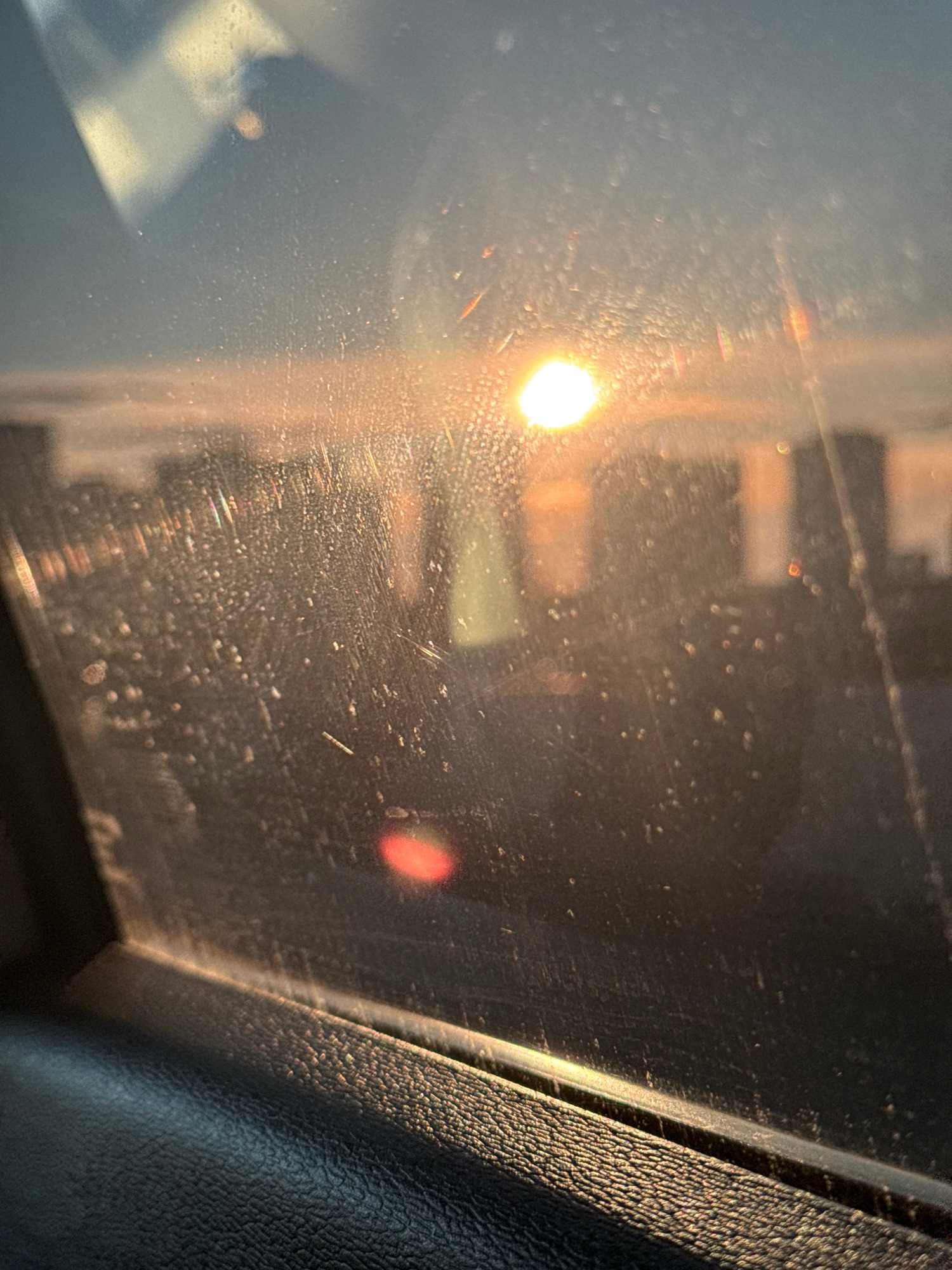 Car window view captures sunlight, urban reflections