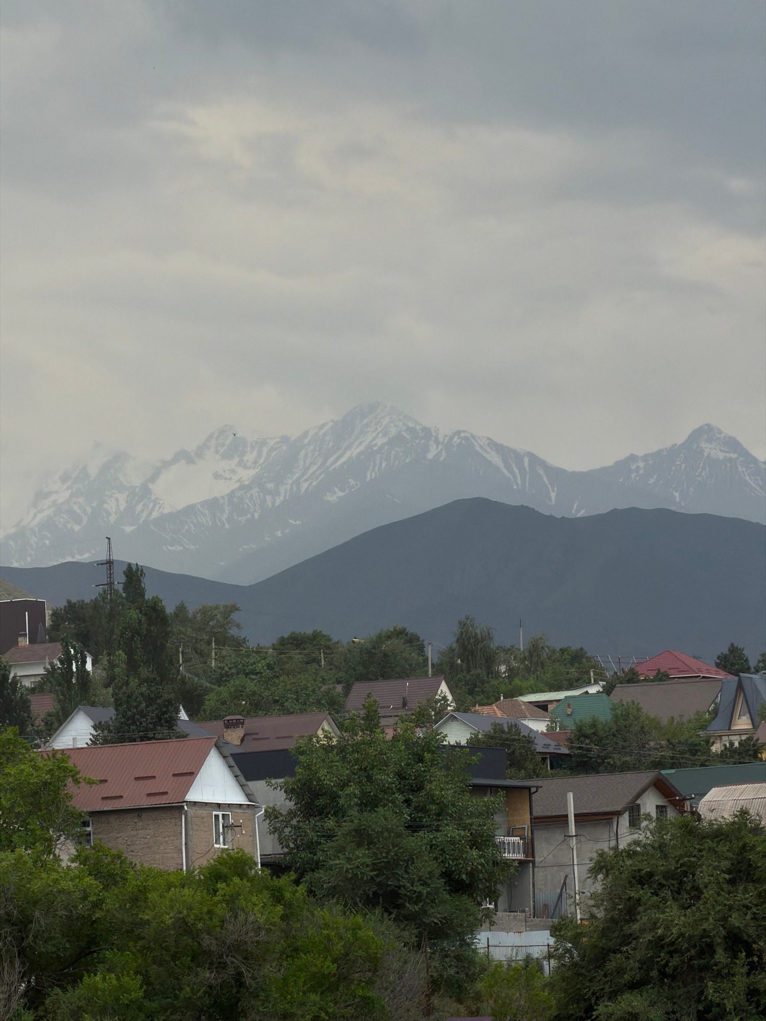 Mountain valley life: horses, livestock, a church, and cloudy peaks