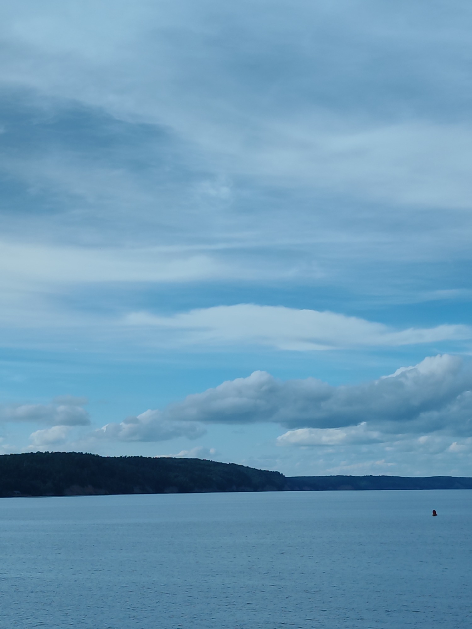Calm waterway with distant shoreline and docked industrial vessels
