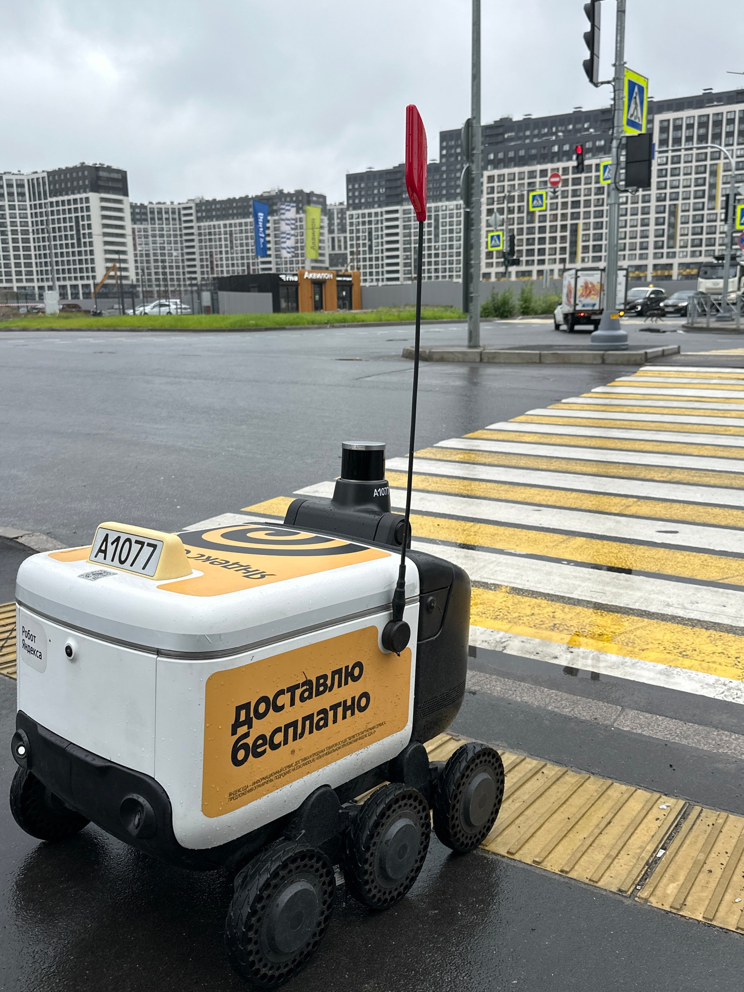 Yandex delivery robot navigates city crosswalks on a rainy day