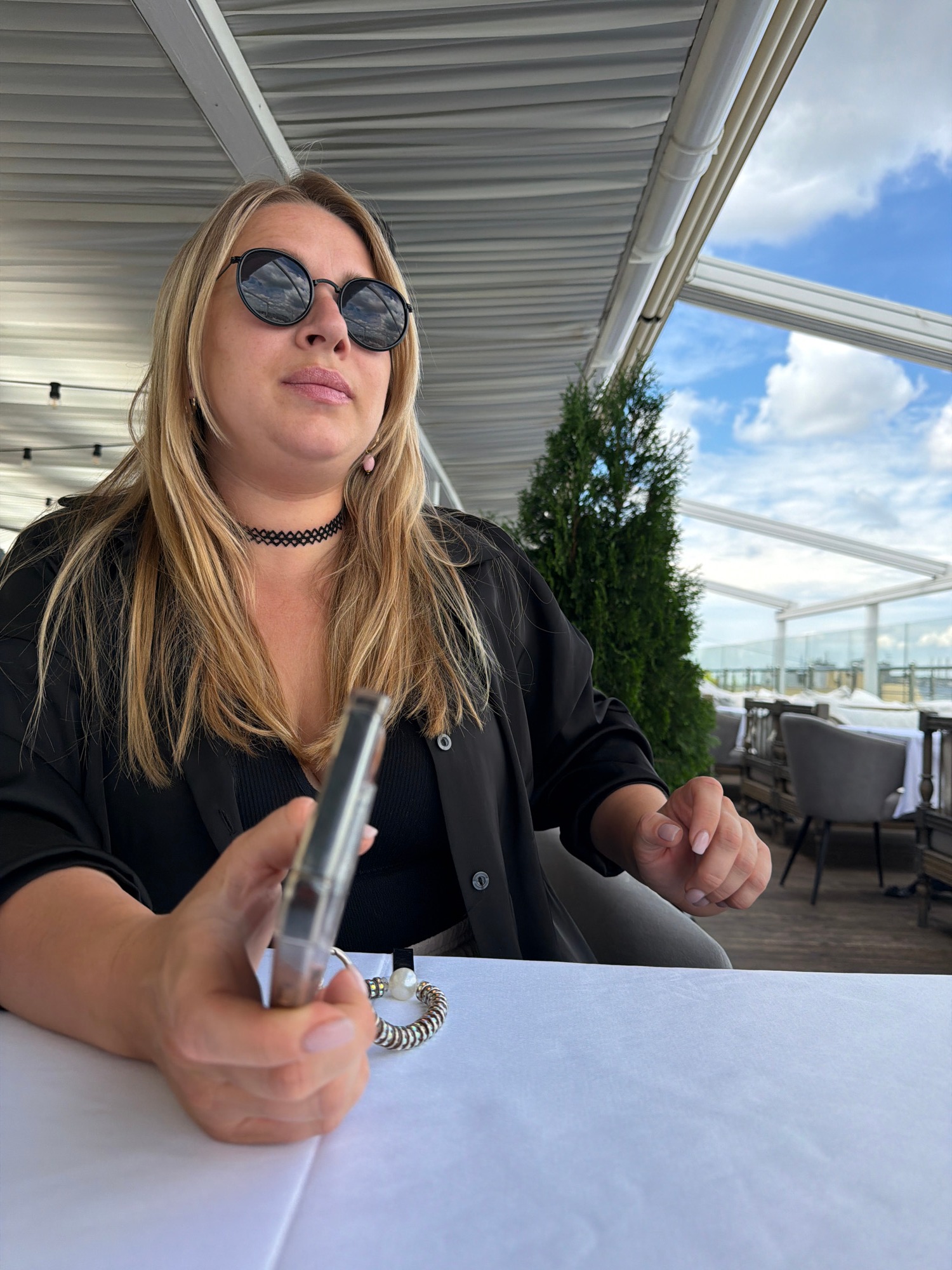 Relaxing at a rooftop terrace table, phone in hand.