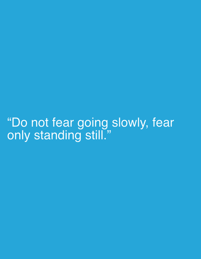 The image is a digital graphic featuring a quote in white text against a solid blue background. The quote reads, "Do not fear going slowly, fear only standing still." The text is centered horizontally on the image and appears in two lines. There are no other visual elements or context provided in the image that would suggest a specific location in Kołobrzeg, Poland, or any other real-world setting.