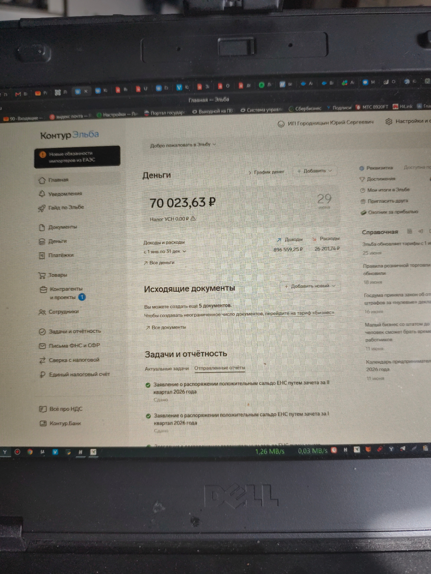 The image shows a laptop screen displaying the web interface of "Kontur Elba," an accounting and business management software. The user's name, "ИП Городниции Юрий Сергеевич," is visible, indicating the owner of the account. The interface shows financial information, including a current balance of "70 023,63 P," and sections for "Documents," "Payments," "Contracts," and "Tasks and Reporting." The lower part of the screen displays network activity with "1,26 MB/s" and "0,03 MB/s." The laptop is placed on a dark surface, likely a desk or table, and part of the laptop's brand name "DELL" is visible at the bottom. There are no people visible in the image. The image is a screenshot of a computer screen, and there is no information that would allow for determining a specific location in the city of Bor, Russia.