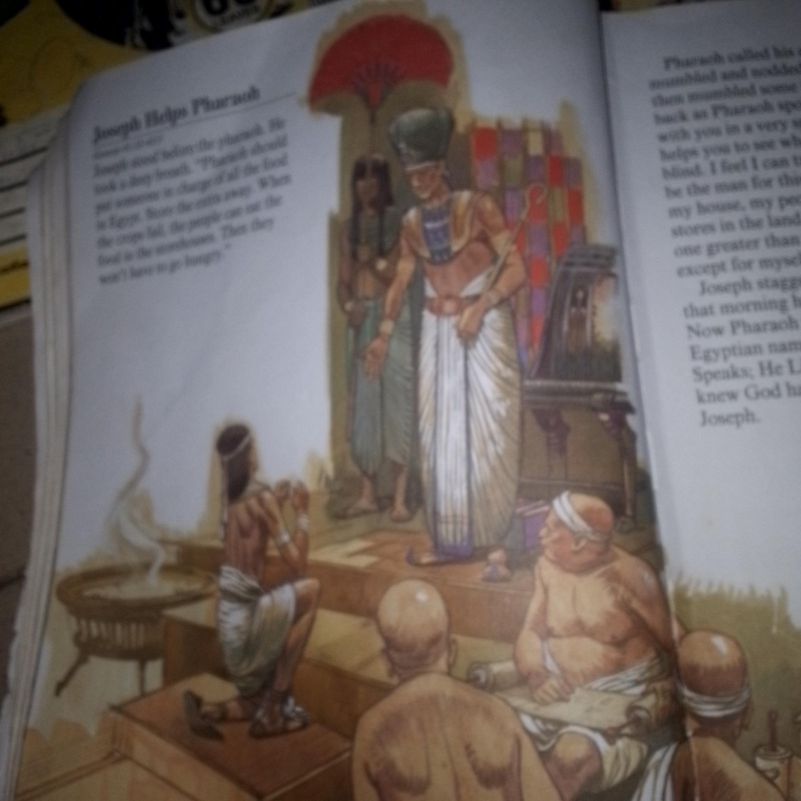 The image depicts an interior scene with several figures rendered in a classical artistic style, likely an illustration from a historical or religious text. In the center foreground, a man identified by text as Joseph stands before a regal figure, presumably Pharaoh, who wears an elaborate headdress and ornate clothing. Joseph appears to be speaking or presenting information. Behind Joseph, another figure in simpler attire stands. To the left, a woman is depicted kneeling, her head bowed, in front of a large, intricately designed circular object, possibly a table or offering stand with a plume of smoke or mist rising from it. In the right foreground, two figures are seated. One is a large man with a prominent belly, leaning forward and appearing to read or examine a scroll. The other figure, facing away from the viewer, is also seated. The background features architectural elements and decorative panels, suggesting an ancient Egyptian setting. The overall lighting is soft, illuminating the figures and objects within the scene. The text accompanying the illustration provides context, with a title "Joseph Helps Pharaoh" and narrative details about Joseph's advice to the Pharaoh regarding food storage during times of famine. The scene appears to be set within a royal court or a place of importance in an ancient city.