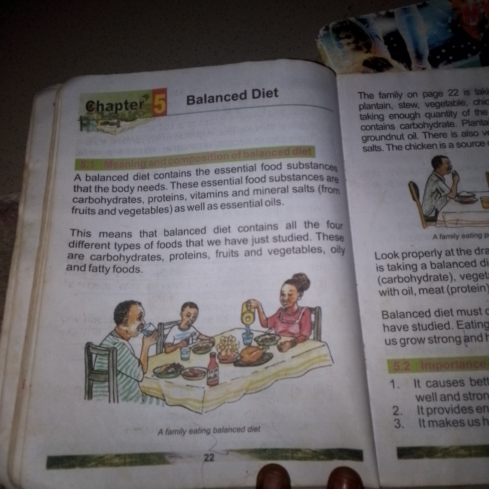 The image shows a page from a textbook titled "Chapter 5 Balanced Diet". The text discusses the meaning and composition of a balanced diet, listing essential food substances like carbohydrates, proteins, vitamins, mineral salts, and oils. It also mentions that a balanced diet contains all the four types of foods. There is an illustration of a family eating a meal, with individuals at a table laden with food. The page also includes a section on the importance of a balanced diet, with numbered points describing its benefits. The text on the right side of the page refers to a "family on page 22" and their meal, which includes plantain, stew, vegetable, and chicken. The illustration is a drawing and not a photograph. There is no information within the image that indicates the location as Jauro Yinu, Nigeria.
