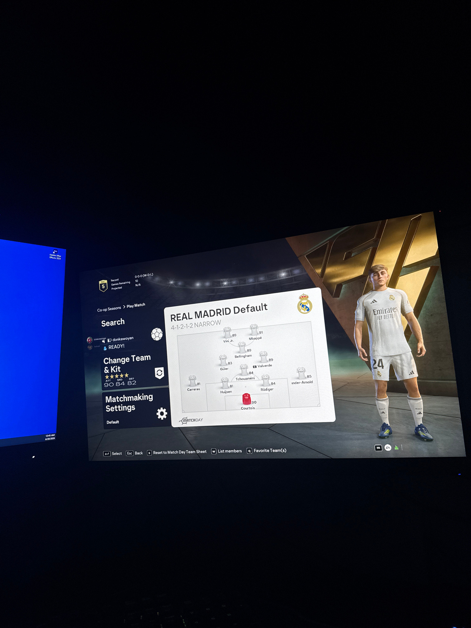 The image shows a screen displaying a video game interface, likely FIFA, given the presence of player ratings and team formations. The game screen features the "REAL MADRID Default" team with a "4-1-2-1-2 NARROW" formation. Several player names, such as Viní Jr., Mbappé, Bellingham, Valverde, Tchouaméni, Rüdiger, Carreras, Huijsen, and Courtois, are visible with their respective ratings. A 3D model of a soccer player in a white Real Madrid kit with the number 24 is prominently displayed on the right side of the screen. The interface also includes options for "Search," "Change Team & Kit," and "Matchmaking Settings." The background appears to be a dark, possibly stadium-themed, environment. There is no visible indication of the city of Shumen, Bulgaria, in the image.
