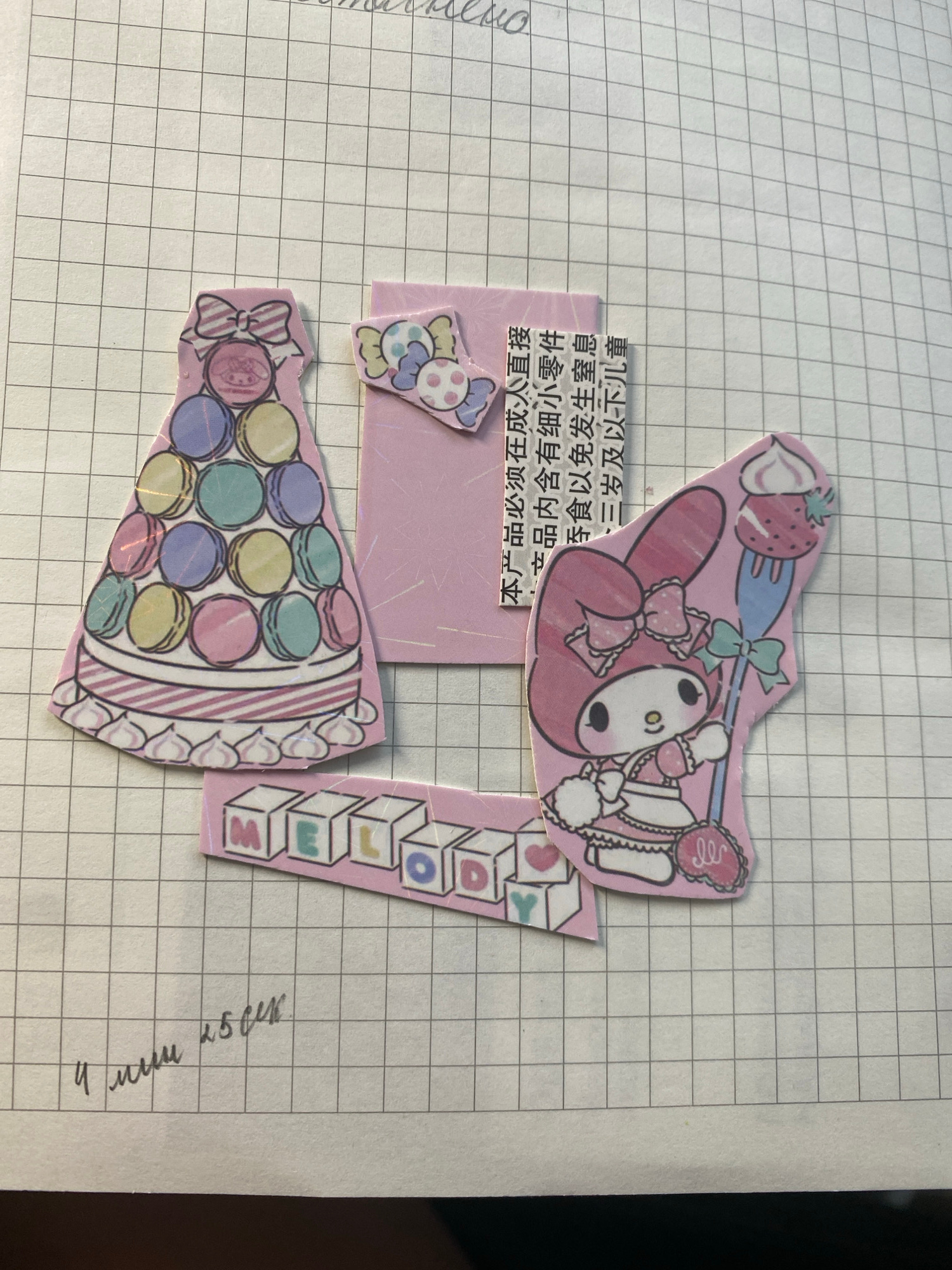 The image shows a close-up of a notebook with a grid pattern, featuring several cute, cartoonish stickers. One sticker depicts a tiered cake made of macarons with a bow on top. Another sticker shows a character, possibly My Melody, holding a fork with a strawberry on it. There's also a sticker with blocks spelling out "MELODY" and a small sticker with candies. A pink paper with Chinese text is partially visible behind some of the stickers. In the bottom left corner of the notebook, there is handwritten text in Russian. The image does not depict a location in Moscow, Russia, or any people or actions.