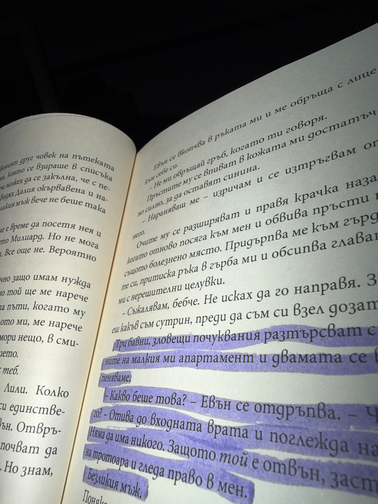 The image shows an open book with Bulgarian text. The book pages are slightly yellowed and textured. The left page has text printed in black ink. The right page has text printed in black ink with several lines highlighted in purple marker. The text is written in Cyrillic script. The lighting suggests a bright, possibly natural light source, casting shadows on the pages. The background is dark and out of focus, indicating a shallow depth of field. There are no people or specific locations in Shumen, Bulgaria, identifiable in the image.