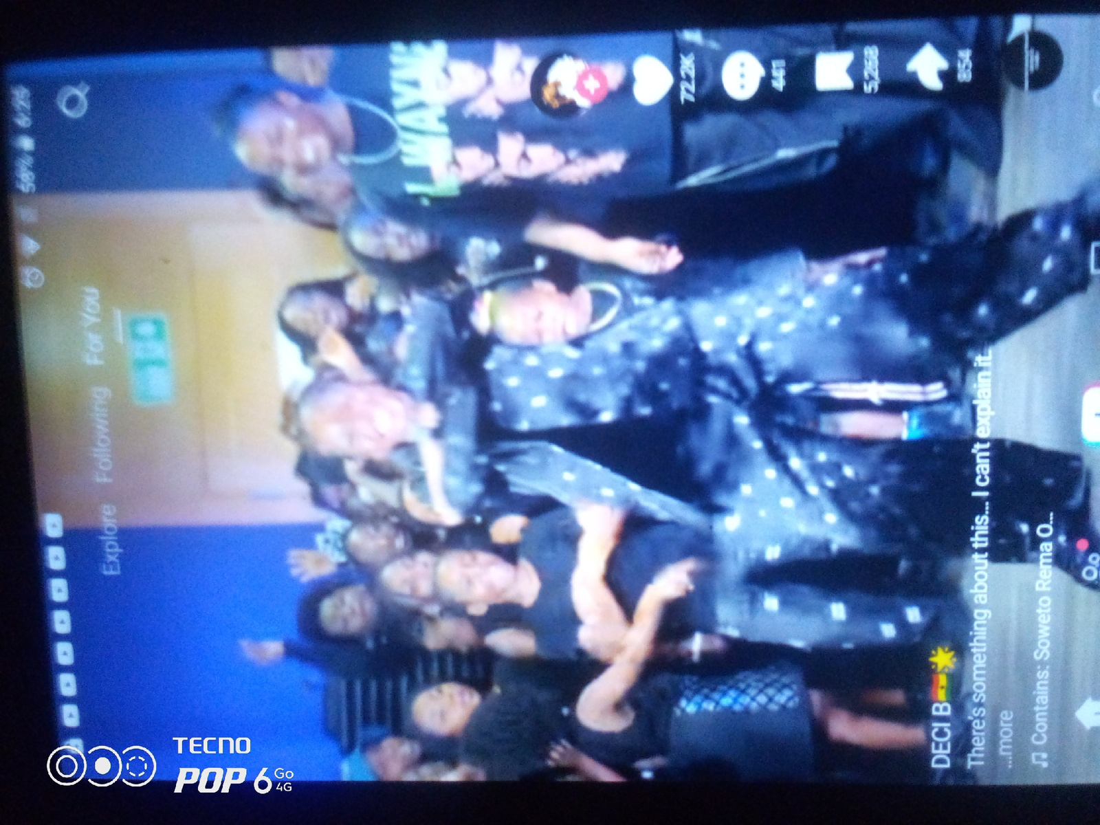 The image shows a vertical screen displaying a video with multiple people. The video is likely from a social media platform, as indicated by icons for likes, comments, and shares, along with a view count of 72.2K. The people in the video appear to be dancing or performing, and many are wearing dark clothing with white patterns. The Tecno Pop 6 4G logo is visible in the bottom left corner, indicating the device on which the video is being viewed. The overall scene suggests a lively event or performance, but there is no specific information about the location in Howayi, Nigeria.