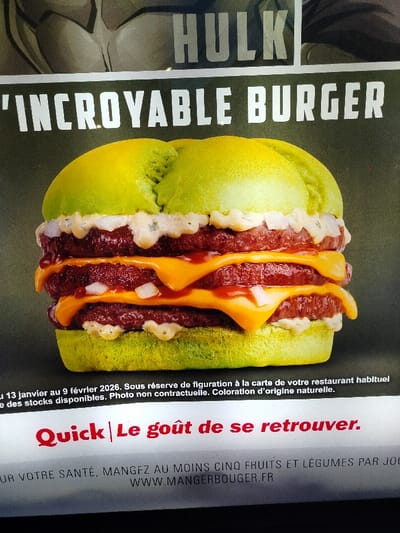 The image shows an advertisement for a "Hulk" 'Incroyable Burger' from Quick restaurant. The burger has green buns, two meat patties, cheese, and a white sauce. The ad includes a statement that the burger is available until February 9, 2026, and that the photo is not contractual and the color is of natural origin. A health message encourages eating at least five fruits and vegetables per day.