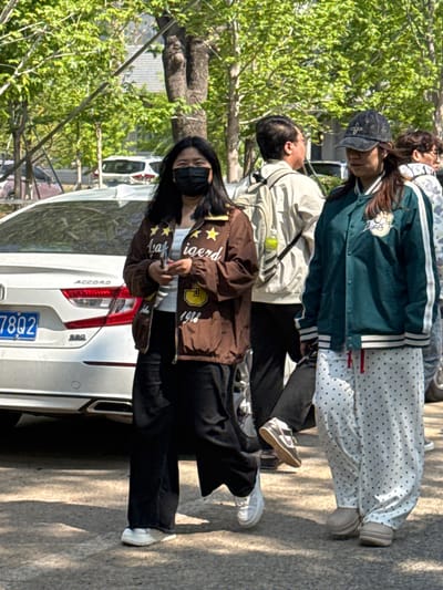 The image shows a group of four individuals standing next to a white Honda Accord, likely in Zhongtun, China based on the license plate. The person nearest the camera is wearing a brown jacket with stars and a black face mask, and black pants. Behind them is a person wearing a light-colored jacket, and behind them are two other people. The car has license plate number 78Q2. The setting is outdoors.