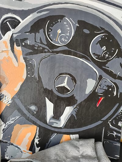 This is a painting of a car's interior, viewed from the driver's perspective. The primary focus is the steering wheel, which features the Mercedes-Benz logo prominently in its center. The dashboard is also visible, with various gauges and indicators rendered in shades of gray, white, and black. A hand, painted in orange and grey tones, is shown on the left side of the steering wheel, suggesting the act of driving or preparing to drive. The overall aesthetic is abstract and stylized, with bold brushstrokes and a limited color palette. There are no discernible details about the time of day, weather, or specific location beyond it being inside a car. No visible text is present in the image.
