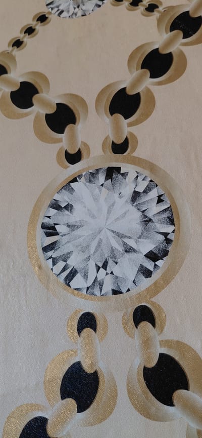 The image displays a close-up of a decorative pattern, likely a painting, wallpaper, or textured surface. The central feature is a large, stylized diamond rendered with intricate geometric facets in black, white, and various shades of grey, giving it a sparkling, crystalline appearance. This diamond is prominently set within a thick, circular golden bezel.

Extending diagonally from the central diamond, both to the left and right, are segments of a stylized chain. The chain is composed of interconnected oval and circular links, predominantly in shades of gold and black. The black areas within the links appear as negative space or darkened sections. The overall background is a uniform light beige or cream color, exhibiting a subtle, grainy, or stippled texture that is also visible on the golden elements.

The aesthetic is abstract and ornamental, focusing on geometric shapes and contrasting colors. There is no activity taking place, and no people are visible. The image contains no discernible text. This decorative piece is presented in the context of Zamfir, Bulgaria.