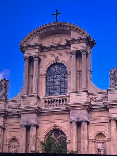 This media file depicts the facade of a building with classical architectural elements, set against a vibrant blue sky. The building features large, ornate columns, arched windows, and decorative sculptures, including what appears to be a cross atop the structure. The architectural style suggests a religious or historical building, possibly a church or cathedral. The overall impression is one of grandeur and historical significance. The lighting suggests it is daytime, with the bright blue sky indicating clear weather. There are no discernible people actively engaged in activity, but statues are present as part of the architecture. The image focuses on the intricate details of the building's exterior. Given the prompt's mention of Dubai, United Arab Emirates, the building's style might be a notable contrast or addition to the typical architecture found in the region, or it could be part of a themed attraction or a preserved historical site. There is no visible text in the image.