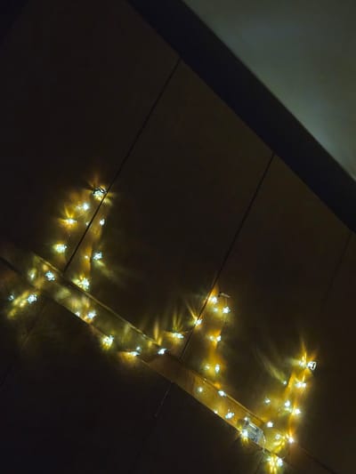 The image depicts a dimly lit surface composed of what appear to be rectangular tiles. A string of novelty lights, shaped like turtles, is draped across the tiles. The lights emit a soft, yellowish glow. The left side of the image is shrouded in darkness, possibly due to a shadow or lack of ambient light. The scene appears to be indoors. There is no evidence in the image to suggest this photograph was taken in Cherkovitsa, Bulgaria, or anywhere specifically.