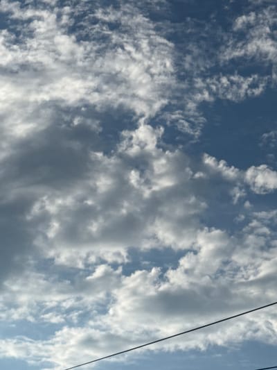 This media file depicts a cloudy sky with a dark wire running diagonally from the top right to the bottom left. The sky is a mix of deep blue and lighter shades, with numerous white and gray clouds scattered across it. Some clouds appear thin and wispy, while others are thicker and more opaque, suggesting varying levels of moisture and atmospheric conditions. The overall impression is of a dynamic sky, possibly indicative of changing weather. The presence of the wire suggests an outdoor setting, likely with human infrastructure nearby, though no specific structures or landscape features are visible. The lighting suggests it is daytime, likely late afternoon or early evening given the slight dimness and the dramatic cloud formations. No text is visible in the image.