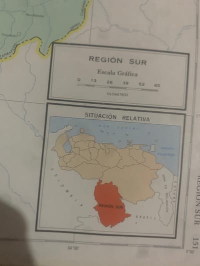 The media file is a photograph of a map, likely from a book or atlas. The map depicts a region labeled "REGIÓN SUR" in Spanish. It shows geographical features such as bodies of water, national borders, and a shaded area highlighting a specific territory. Text on the map includes place names like "CURUPIRA," "ERRA," "TAPIRAPECO," "MAR CARIBE," "OCEANO ATLANTICO," "GUYANA," "ZONA EN RECLAMACIÓN," and "BRASIL." A graphic scale is provided with the label "Escala Gráfica" and marks for "KILOMETROS." Coordinates and other numerical labels are also visible. The map is displayed in a way that suggests it is part of a larger publication, as evidenced by the cropping and the presence of a faint outline of what could be a page edge or binding. The image appears to be taken in daylight, with no significant shadows or lighting effects that would indicate a specific time of day or weather conditions. The focus is entirely on the map itself, with no people, animals, or other living subjects present. The overall impression is that of an educational or informational document.