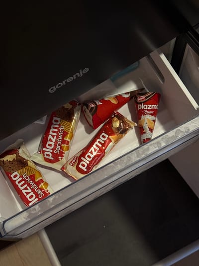 The image shows a drawer inside a Gorenje refrigerator, containing several "Plazma" brand ice cream products. These include "Plazma Cream" cones and "Plazma Sandwich" ice cream bars. The products are packaged in red and white wrappers with the "Plazma" logo prominently displayed. The drawer is white and located inside a black refrigerator. It appears to be in a kitchen or storage area. There are no people visible in the image. There is no visible context to determine if the image was taken in Vozdovac Urban Municipality, Serbia.