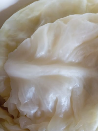 The image shows a close-up, abstract view of layered, pale yellow and white organic material, likely cabbage leaves. The texture is soft and somewhat glossy, with visible veins and folds. There are no discernible features of Hlynytsi, Ukraine, or any human elements in this close-up macro shot.