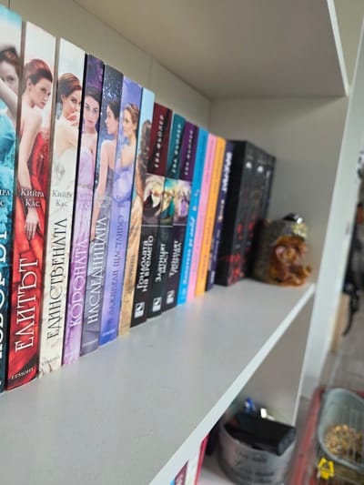 The image shows a collection of books on a shelf. The books are stacked in a row, and their spines are visible. The books appear to be a series, and feature female models on the covers. Above the books on the same shelf are other objects. The location is not discernible as Yagodovo, Bulgaria, or any other specific location based solely on the image.