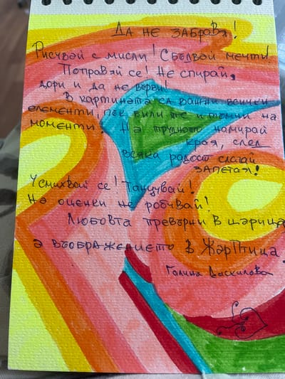 The image is a close-up shot of a piece of paper with a colorful, abstract watercolor background. The background consists of concentric semi-circles and radiating lines in shades of yellow, orange, red, pink, and blue, creating a vibrant and energetic visual.
Handwritten text in black ink is overlaid on the watercolor. The text appears to be a poem or inspirational message in Bulgarian. The writing is in a cursive script and is oriented diagonally across the page. There is also a small, stylized drawing of a heart-shaped object with a swirling tail above and to the right of the main body of text.
The visible text reads:
"Да не забрава!
Рисувай с мисли! Сбъдвай мечти.
Поправай се! Не спирай,
дори и да не върви!
В картината са важни всички
елементи, пък били те и томни на
моменти! На трудното намирай
края, след
Всяка радост слагай
запетая!
Усмихвай се! Танцувай!
На оценен не робивай!
Любовта превърни В царица
а въображението в ЖарПтица.
Галина Даскалова"
The overall impression is one of creativity, joy, and encouragement, conveyed through both the visual art and the written words. The paper appears to be part of a notepad, with the spiral binding visible on the left edge. The lighting suggests it might be daytime, with natural light illuminating the artwork. The textures of the watercolor paper are visible, adding to the tactile quality of the image.