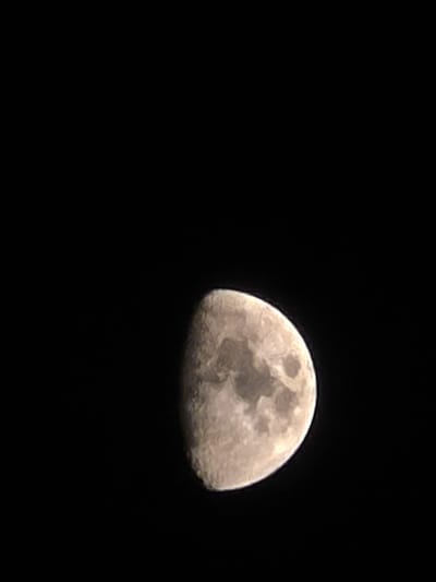 The image shows a close-up view of the moon against a dark, black sky. The moon is partially illuminated, with its rough, textured surface clearly visible. Craters and other geological features are discernible on the moon's surface, suggesting a detailed capture. The lighting on the moon indicates that it is not a full moon, but rather in a phase where a significant portion is still in shadow.

The setting is nighttime, as indicated by the black sky. There are no visible clouds or atmospheric effects, suggesting clear weather conditions. The composition of the image, with the moon occupying the right side and leaving the majority of the frame as empty black space, creates a dramatic and focused view of the celestial body.

There is no visible text in the image. The location context of Yambol, Bulgaria, provides geographical information but is not visually represented in the image itself. The image is a static shot of the moon and does not depict any ongoing activity or event other than the natural presence of the moon in the night sky. No people are present, and the primary subject is the moon. The overall mood is one of quiet observation of space.