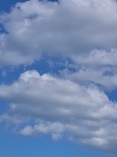 This media file captures a close-up view of a bright blue sky filled with white and gray clouds. The clouds are varied in texture and density, with some appearing fluffy and soft, while others are more wispy and translucent. Sunlight is filtering through the clouds, creating a sense of depth and illumination. The image focuses solely on the sky, with no ground features or horizon visible. This suggests the photo was taken from a high vantage point, possibly from an airplane or a very tall structure, or it is a cropped image. The scene evokes a feeling of openness and natural beauty, typical of a clear day with scattered cloud cover. The time of day appears to be daytime, given the brightness of the sky and the sunlight. There are no people, objects, or text visible in the image.