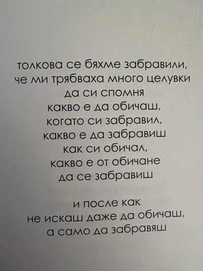 The image is a close-up, high-angle shot of a poem printed on a textured, off-white surface. The text is in Bulgarian, set in a dark, sans-serif font, and appears to be printed or very finely etched.

The poem reads:

"толкова се бяхме забравили,
че ми трябваха много целувки
да си спомня
какво е да обичаш,
когато си забравил,
какво е да забравиш
как си обичал,
какво е от обичане
да се забавиш

и после как
не искаш даже да обичаш,
а само да забравяш"

This translates to:

"We had forgotten ourselves so much,
that I needed many kisses
to remember
what it is to love,
when you have forgotten,
what it is to forget
how you loved,
what it is from loving
to delay

and then how
you don't even want to love anymore,
but only to forget"

There are no people, objects, or environmental details visible in the image beyond the text and the surface it is printed on. The location in Pazardzhik, Bulgaria, is not determinable from the visual content of the image.