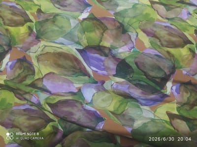 The image displays a close-up, top-down view of a fabric with a watercolor-style pattern of overlapping leaves. The leaves are rendered in various shades of green, purple, and brown, with some lighter yellow and white accents. The style is abstract and impressionistic, with soft edges and blended colors. The fabric appears to be silk or a similar lightweight material, as suggested by the subtle sheen and drape.
The scene is static, focusing entirely on the textile pattern. There are no people, specific objects other than the fabric itself, or a discernible setting beyond what can be inferred from the textile design. The lighting is diffuse and even, suggesting an indoor environment or an overcast day. There are no explicit indicators of weather or time of day beyond the text overlay.
Visible text in the bottom left corner reads "REDMI NOTE 8" and "AI QUAD CAMERA" in white lettering, indicating the device used to capture the image. In the bottom right corner, a date and time stamp reads "2026/6/30 20:04". The location context provided is Baýramaly, Turkmenistan, which is external information not visually present in the image itself. The overall mood is calm and artistic, emphasizing the aesthetic qualities of the fabric's design.