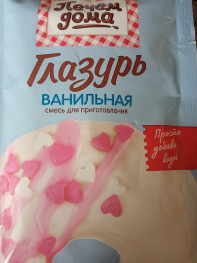 The image shows the packaging of a product, likely a food item, with text in Russian. The word "Глазурь" (Glaze) is prominently displayed in brown, with "ВАНИЛЬНАЯ" (Vanilla) in blue underneath. Further down, the text "смесь для приготовления" (mixture for preparation) is visible. At the top of the package is the brand name "Печём дома" (We bake at home) in stylized text over a red and white checkered banner. The lower part of the package depicts a frosted donut with pink and white heart-shaped sprinkles and pink frosting. A red banner on the right side states "Просто добавь воды" (Just add water). There's no indication of the location of Elektrostal, Russia. The image is a close-up shot of the packaging itself.