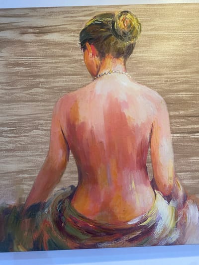 This is a painting of a person seen from behind. The person has dark hair styled in a bun and is wearing a pearl necklace. They are wearing a colorful, draped garment that appears to be made of fabric with a patterned design. The background is a textured wash of light brown and beige, creating a sense of depth and a neutral setting. The painting style is impressionistic, with visible brushstrokes that add texture and movement to the image. The lighting in the painting appears to be soft and diffused, suggesting an indoor setting or perhaps a subdued outdoor environment. There is no visible text in the image.