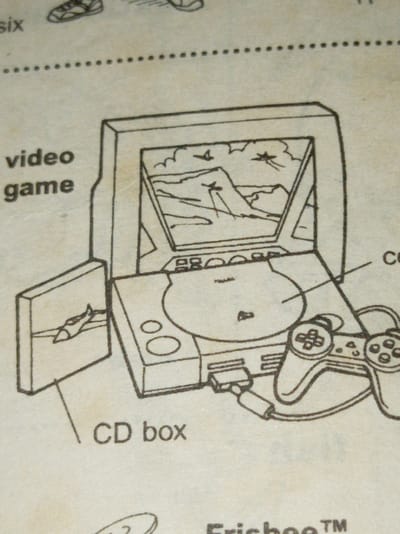 The image is a line drawing of a video game console, a game controller, a CD box, and a screen. The game console appears to be a first-generation PlayStation. The CD box is depicted to the left of the console, and the controller is on the right. The screen shows a landscape with what looks like airplanes. The words "video game" and "CD box" are written next to the depicted objects. The word "six" is written above the drawing along with a shoe and other graphics. The city of Owerri, Nigeria is not referenced in the image.