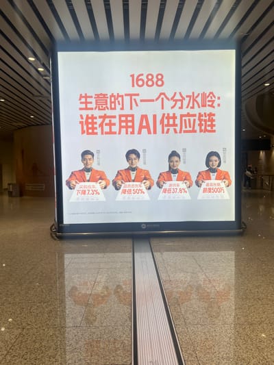 The image shows a large illuminated billboard in a modern, indoor public space, possibly an airport or convention center, based on the high ceilings and minimalist architecture. The billboard features an advertisement for "1688" and the text "生意的下一个分水岭:谁在用AI供应链" which translates to "The next watershed moment for business: Who is using AI supply chain?". The advertisement displays four AI-generated individuals in orange jackets, each holding a placard with statistics related to AI in supply chain management. The first person holds a placard stating "采购成本 下降 7.3%" (Procurement costs decreased by 7.3%). The second shows "品质退货率 降低 50%" (Quality return rate reduced by 50%). The third has "断供率 降低 37.8%" (Supply disruption rate reduced by 37.8%). The fourth displays "最高账期 额度500万" (Highest payment term: 5 million yuan limit). Below the main advertisement, there is a disclaimer in smaller text. The floor is polished and reflects the light from the billboard and surrounding environment. The overall impression is a promotional display for a business solution leveraging artificial intelligence. The location of Guangzhou City, China is not explicitly visible in the image, but the Chinese text suggests its origin.