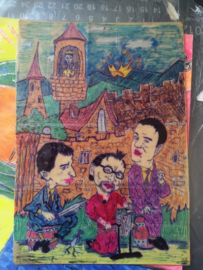The image appears to be a drawing or illustration of a caricature scene, possibly inspired by a medieval setting. In the background, there is a castle or fortress with towers and a king-like figure looking out from the window of one of the towers. The background includes mountains, a sunset, and various buildings with red roofs. In the foreground, there are three caricatured men. One man is seated holding a sword, another is kneeling, turning a crank that is connected to a metal object, and the third man sits on a barrel holding his hands up. All three men are wearing suits, and are wearing red lipstick. The drawing style is reminiscent of pen and ink with color shading. The Karnobat, Bulgaria reference cannot be confirmed from the visual information.