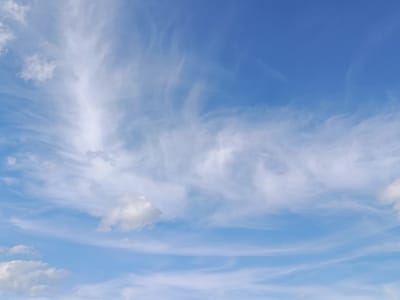 This media file captures a wide expanse of a bright blue sky filled with wispy, white clouds. The clouds are scattered across the frame, with some appearing as thin, elongated streaks, while others are more puffy and defined. The overall impression is that of a clear and pleasant day. There are no people, objects, or specific structures visible, focusing entirely on the natural beauty of the sky. The time of day appears to be daytime, likely mid-morning or afternoon, given the brightness of the sky and the sunlight illuminating the clouds. The weather seems to be fair and possibly breezy, as suggested by the form of the clouds. There are no discernible location cues within the image itself, but external context places it in the Lahojsk selsaviet, Belarus. No text is visible in the media file.