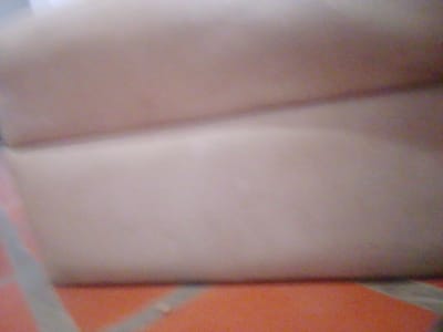The image is a low-resolution, blurry photograph that appears to be taken indoors. The dominant colors are muted shades of beige, pink, and orange. The foreground shows an orange surface with some diagonal lines, possibly indicating tiles or a patterned floor. Above this, the image transitions to a lighter, beige surface that seems to be textured, perhaps a wall or furniture. There is a distinct horizontal line separating these two areas. The upper portion of the image is a lighter, more uniform beige, possibly a ceiling or another wall. The overall impression is of a dimly lit, somewhat cluttered domestic or commercial space. No specific landmarks or identifiable objects are visible due to the blurriness. Without further context or clearer details, it is impossible to determine the exact location within Atamo Sur, Venezuela.