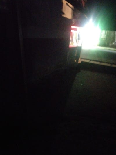 A poorly-lit photograph taken outdoors at night depicts the rear corner of a vehicle and its tail light, with other light sources obscured by lens flare. The foreground is largely obscured by darkness. The exact location is unclear, making confirmation of it being Uyo, Nigeria impossible to confirm based on this image alone. No people are directly visible.