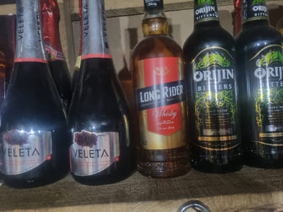 The image shows several bottles of alcoholic beverages. Two bottles labeled "VELETA" feature grape imagery and "RED GRAPE" text. A bottle of "LONG RIDER" whisky is visible, along with two bottles of "ORIJIN BITTERS," characterized by green leafy designs. The "ORIJIN" bottles also bear the words "SPIRIT DRINK." The bottles are arranged in a row, suggesting a shelf or display.