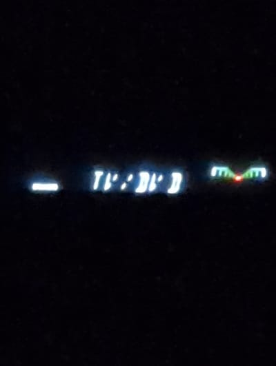 The image shows a digital display with the time "11:21:11" illuminated in white. To the right, a green-and-red light display shows a bar chart with a red light on. The image appears to be taken from a vehicle. The location of the image is not visible, but based on the coordinates, the location would be near Hildesheim, Germany. The scene is dark, with only the digital display and the light bar chart illuminated. There are no people or objects visible in the image besides the digital display. There are no interactions or actions visible.