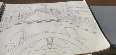 The image depicts a pencil drawing of a go-kart track. The perspective is from the driver's seat, looking forward towards the finish line. The track is lined with fences and has "GAME" written repeatedly along the edges. A checkered finish line is visible in the distance, where a figure holding a checkered flag stands. The drawing style is rudimentary, with an emphasis on perspective. There are no specific geographical markers in the drawing that would indicate its location in Goni Gara, Nigeria, or any other specific city. The drawing is on a spiral-bound notebook.