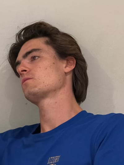 A young, light-skinned person with brown hair and brown eyes is wearing a blue shirt with "AZZURRI" printed on it. They have freckles on their face. The background is a plain, off-white wall. The image does not suggest a location in Florence, Italy, or provide any evidence to indicate it was taken there.
