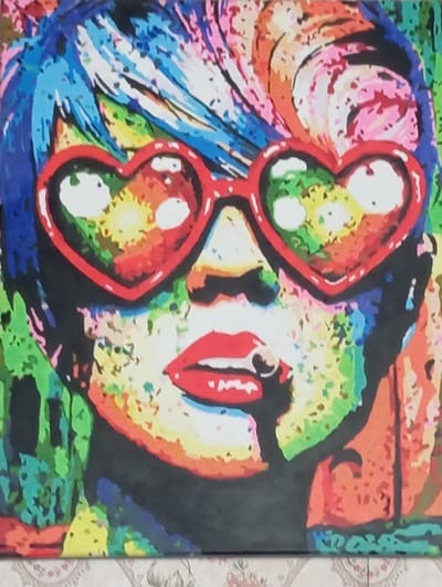 This is a vibrant, pop art style painting of a person's face, viewed in profile. The subject is wearing oversized heart-shaped sunglasses with red rims. The lenses of the sunglasses are filled with colorful swirls of yellow, green, and white. The person's lips are painted bright red and are slightly parted, revealing a glimpse of teeth. Their hair appears to be a riot of colors, with streaks of pink, blue, orange, and yellow. The background is a chaotic blend of various colors and shapes, suggesting a dynamic and energetic atmosphere. There are no visible text elements in the painting. The style is reminiscent of Andy Warhol's iconic portraits, with bold outlines and flat areas of color. The overall impression is one of playfulness and intense visual stimulation. The image does not provide specific cues about the time of day, weather, or a precise location beyond its artistic style.