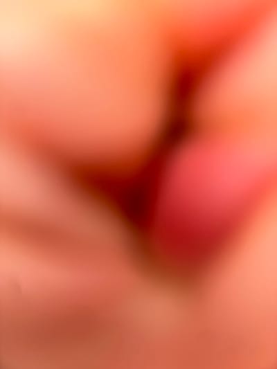 An out-of-focus image reveals an ambiguous view dominated by fleshy tones ranging from light peach to deep red. A dark, triangular shape sits prominently within the field, seemingly an obscured feature, casting shadows that suggest a contoured surface. The overall impression is one of a close-up, unclear organic form, possibly skin or internal tissue, lacking definitive textural details due to the pronounced blur.